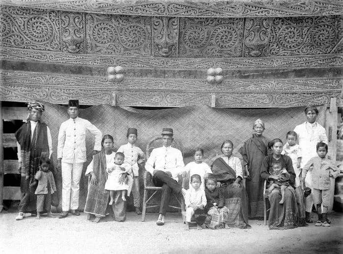 Toba heads with his family in their home with beautifully carved head of Toba family (adathuis) Tapanoeli, North Sumatra, circa 1900.
